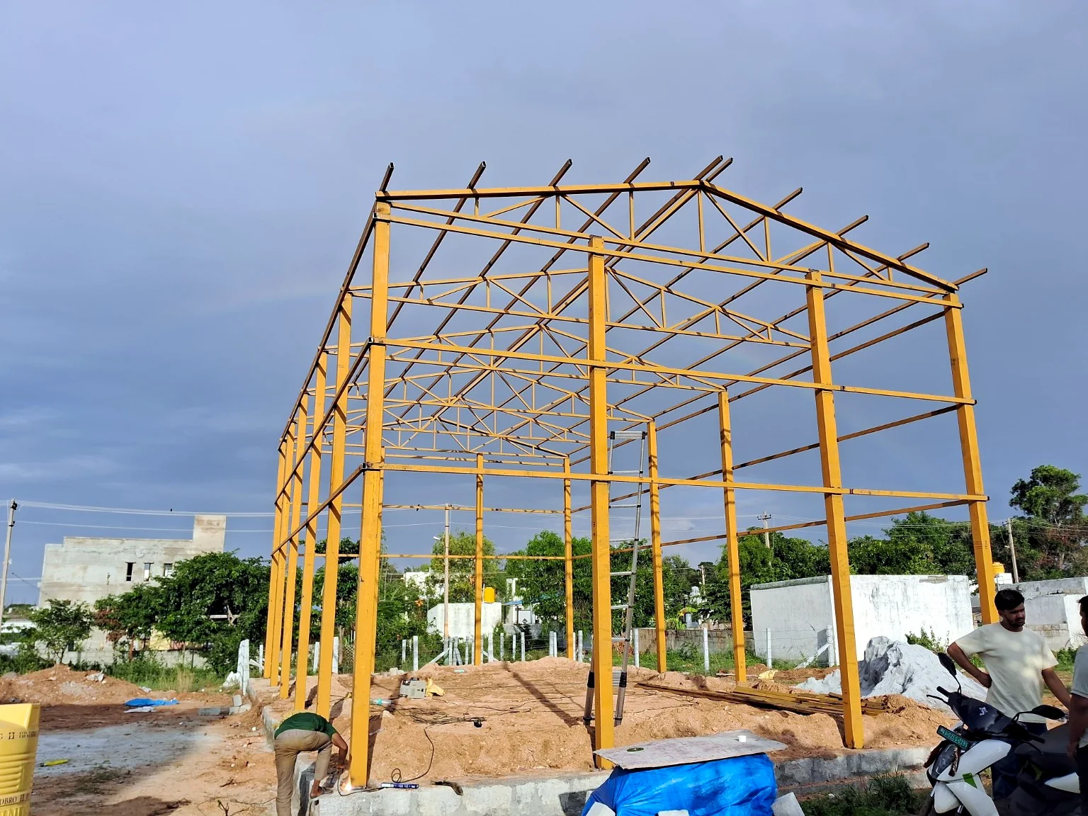 Fabricated yellow steel columns and roof framing for an industrial structure.