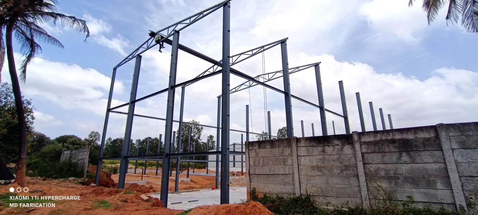 PEB-style steel frame erection with columns and tapered roof members.