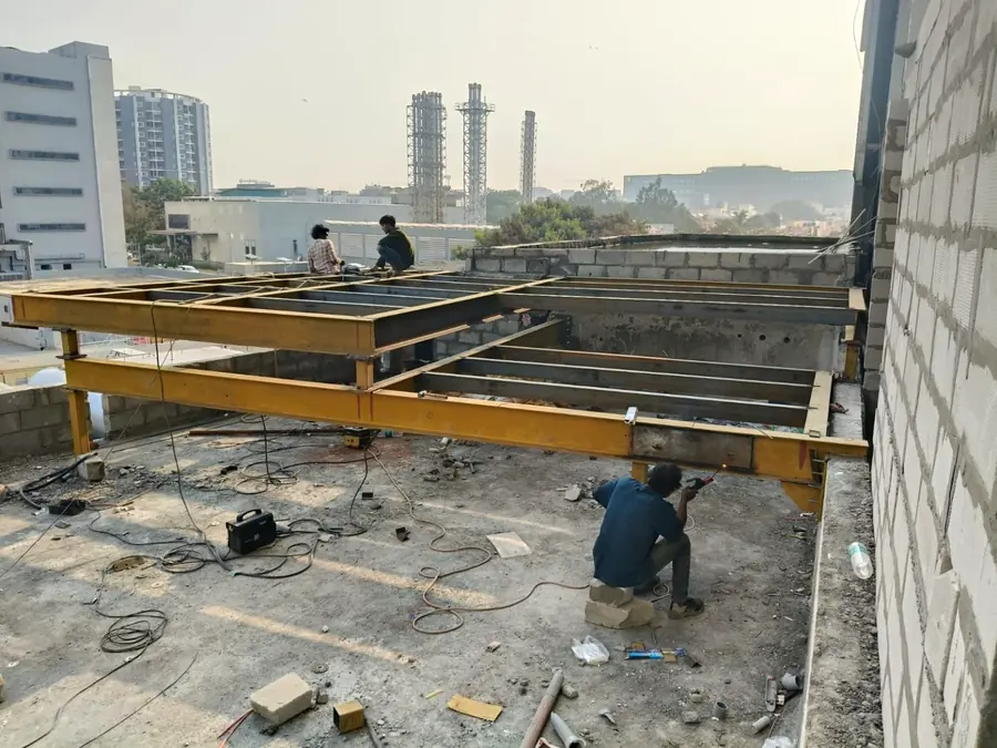 On-site heavy steel fabrication and beam installation at an industrial project.