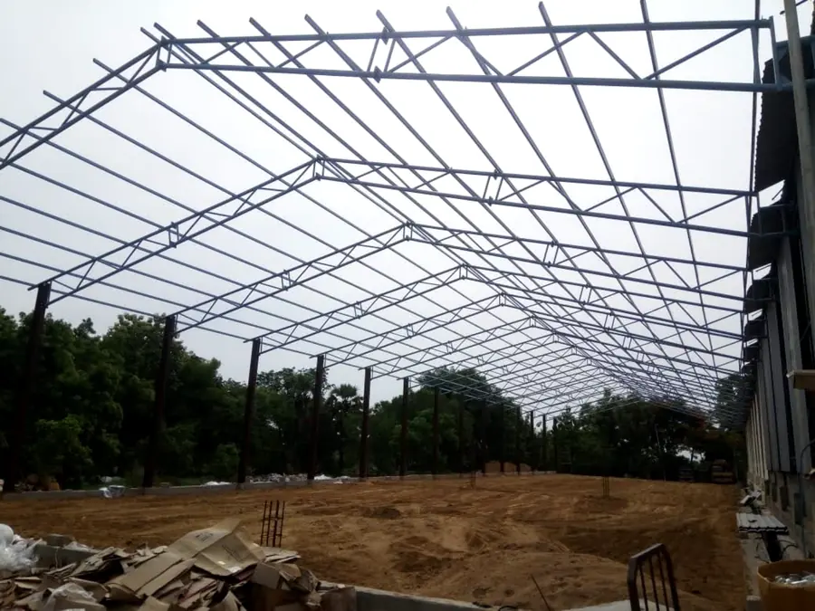 Long-span steel shed framework with repeated trusses and purlins.