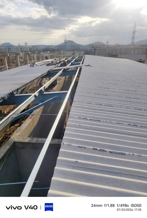 Roof sheet installation underway on a large industrial roof.