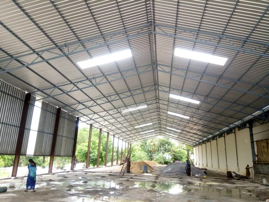 Spacious industrial shed interior with truss roof and metal cladding.