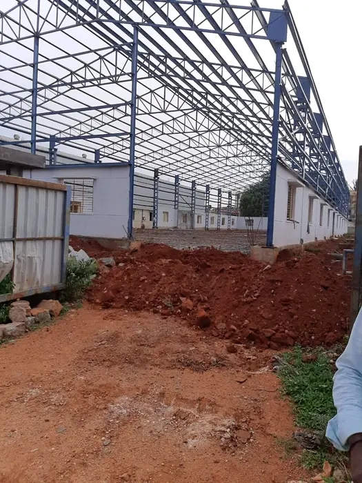 Large blue structural steel shed frame with roof trusses and side framing.