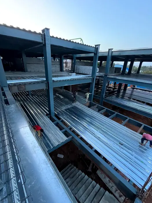 Multi-level structural steel frame with metal deck sheets being installed.