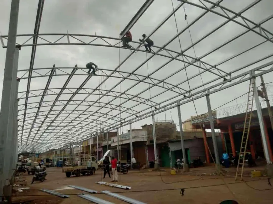 Large steel canopy structure under erection with workers installing purlins.