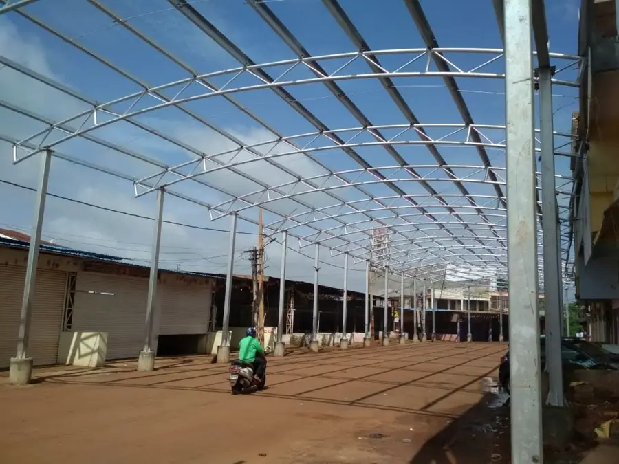 Long-span industrial canopy frame with curved trusses and steel columns.