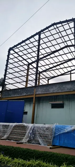 Heavy steel roof frame and purlin grid erected above an industrial building.
