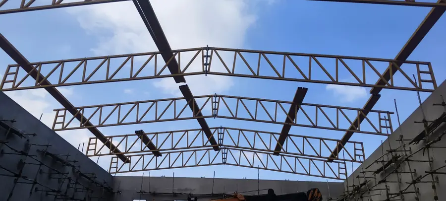 Large steel roof truss framework viewed against the sky.