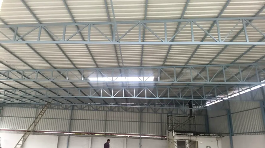 Industrial shed interior showing roof trusses, cladding and daylight openings.