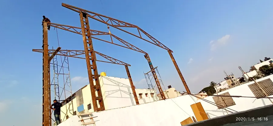 Tall roof truss framework erected over a building under construction.
